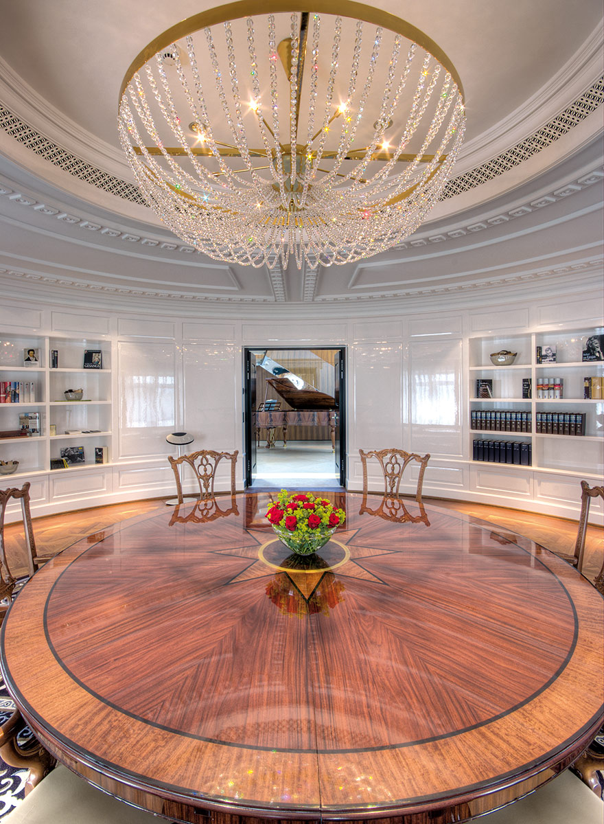 Kronleuchter in der Bibliothek und über großem runden Tisch aus Holz passend zum Flügel im Treppenhaus